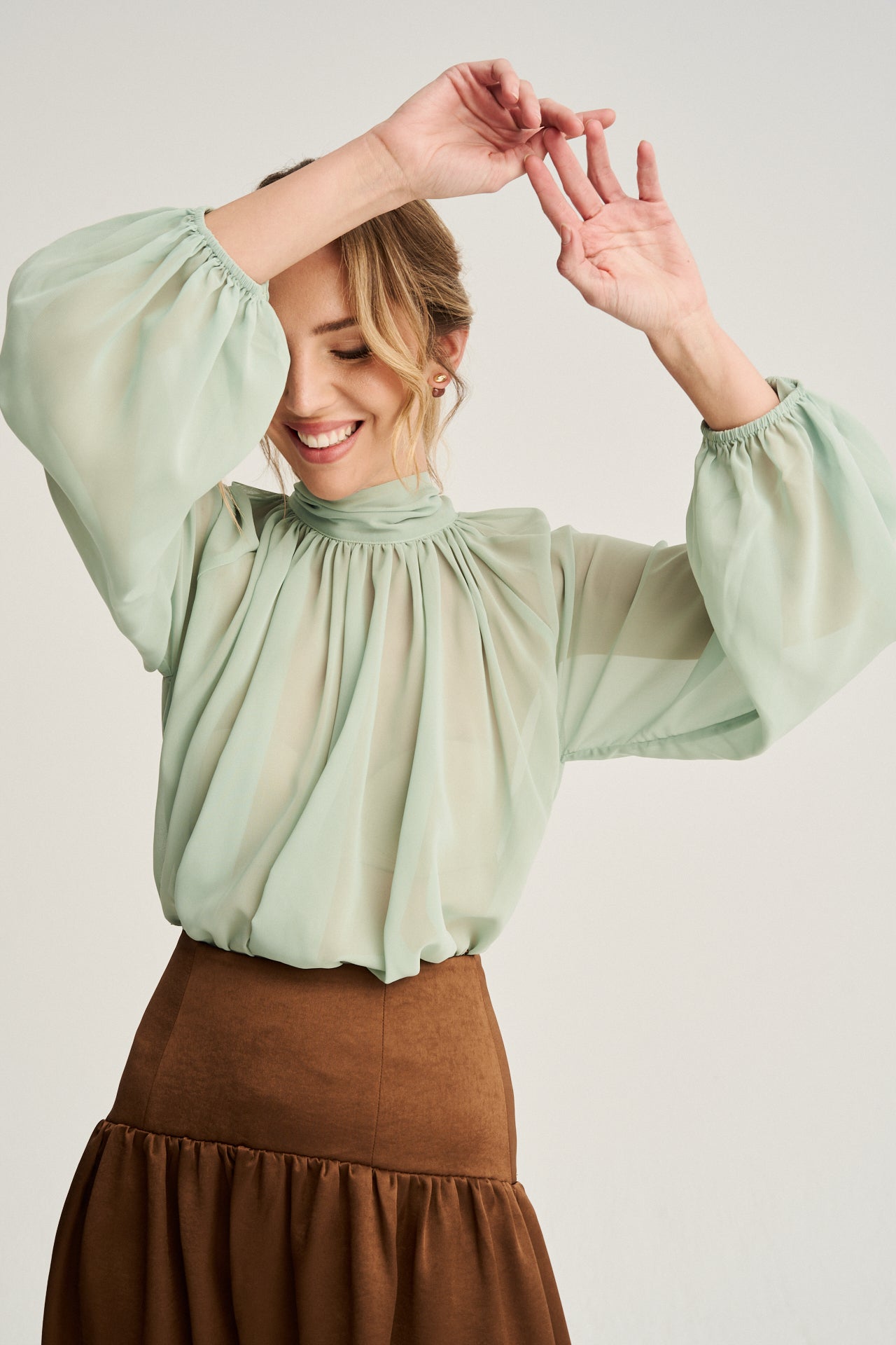 Top fluido en tono seafoam con mangas abullonadas y lazo en el cuello, perfecto para un estilo romántico.