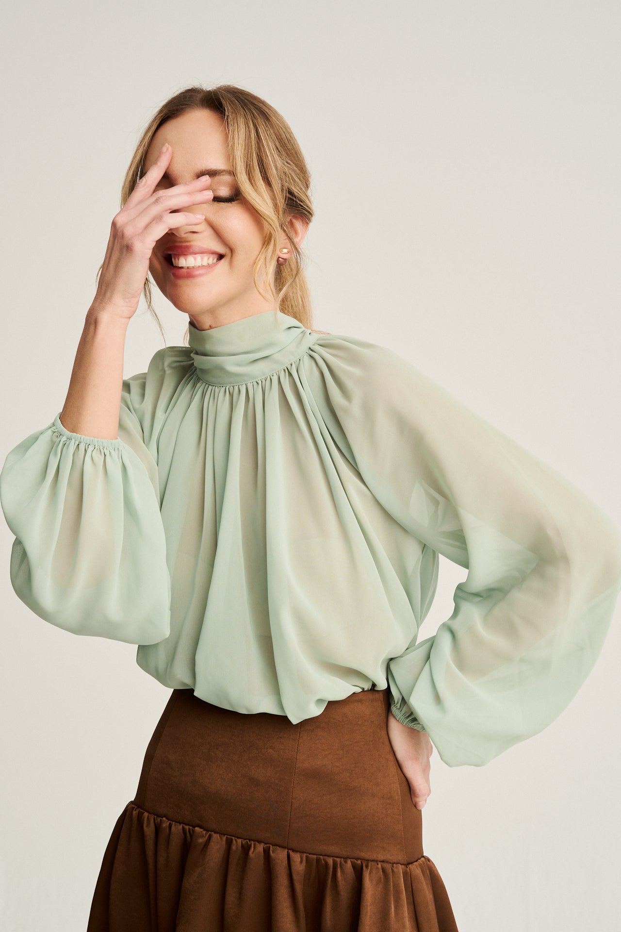 Top oversize en georgette verde menta con cuello alto y lazada, ideal para un look bohemio y sofisticado.