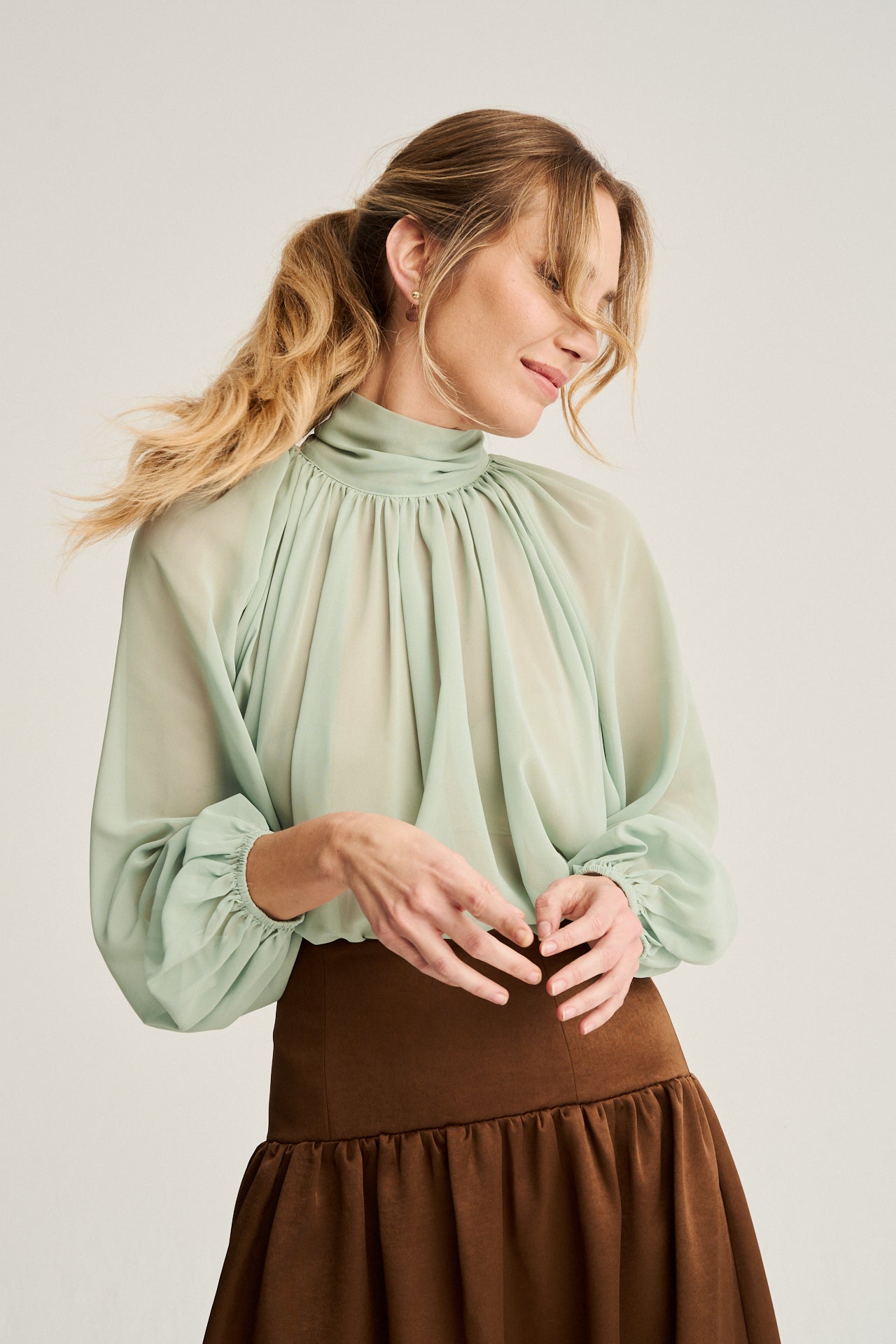 Blusa verde menta de estilo bohemio con cuello alto y lazada, confeccionada en georgette ligero para un look etéreo.