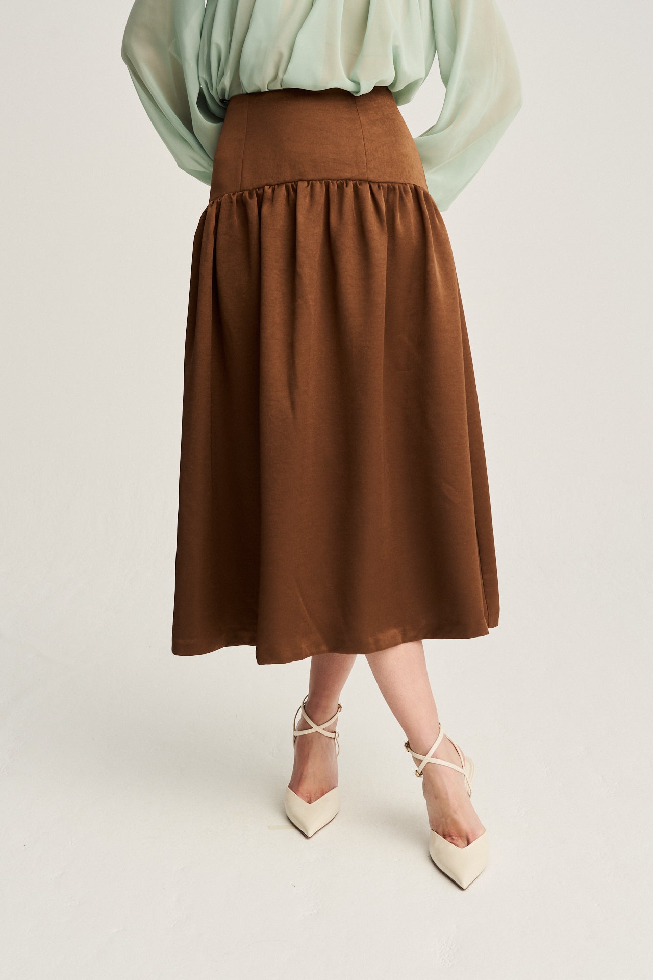 Falda midi en color chocolate con fruncido elegante y tejido tipo tafetán, ideal para un look sofisticado.