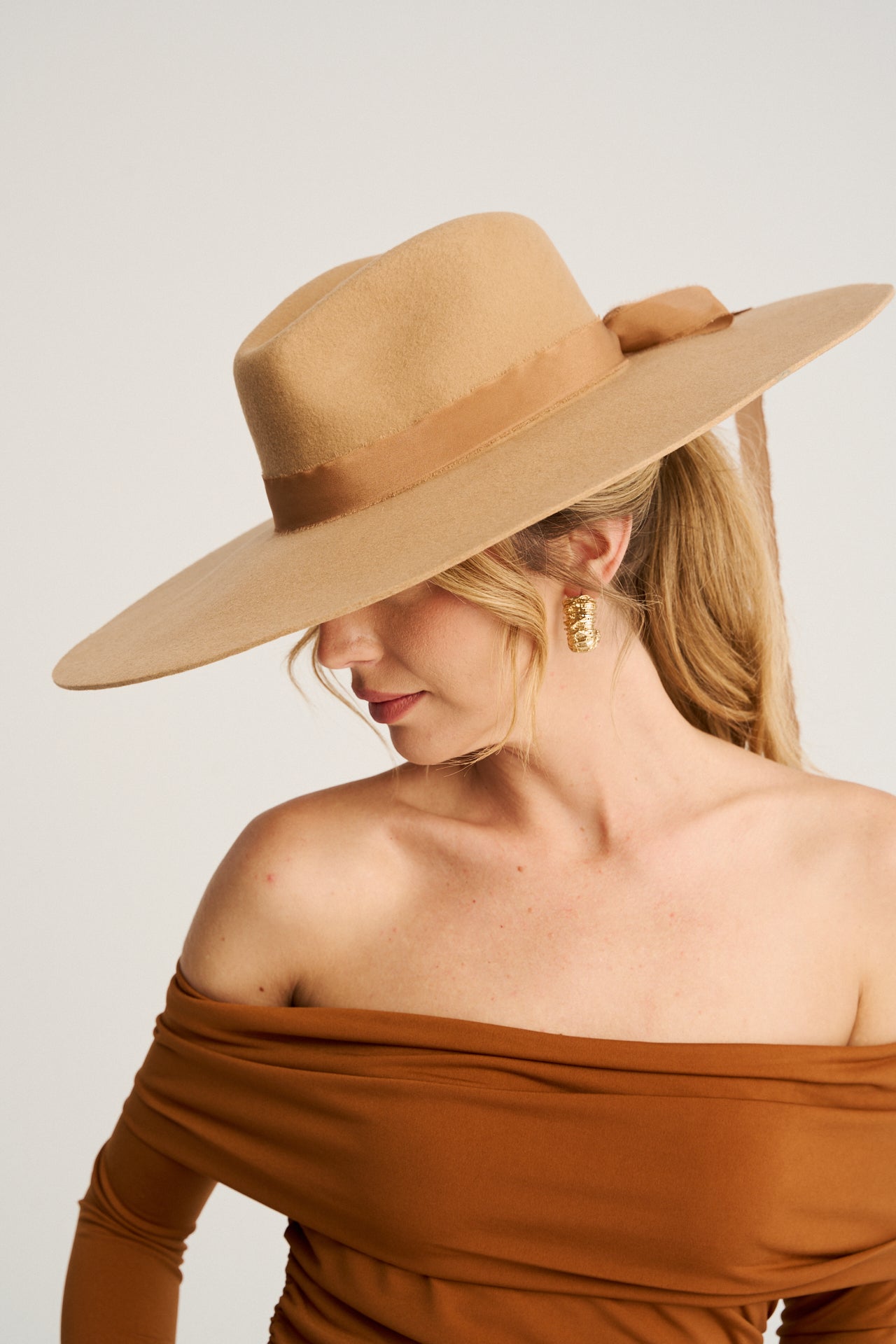 Sombrero Fedora caramelo con ala ancha y detalle de cinta de seda desflecada, ideal para eventos y looks exclusivos.