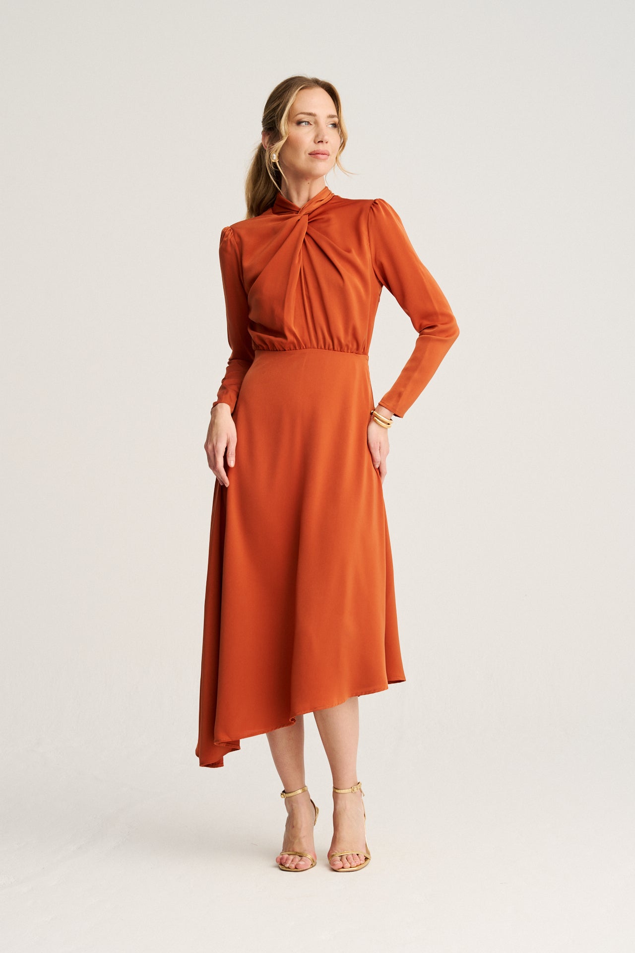 Vestido teja naranja con bajo asimétrico y manga larga, elegante y moderno, ideal para ocasiones especiales.